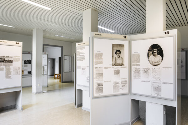 A large room containing exhibition panels. The two panels in the foreground bear the title "Fate", as translated, and show the portraits of two young women.