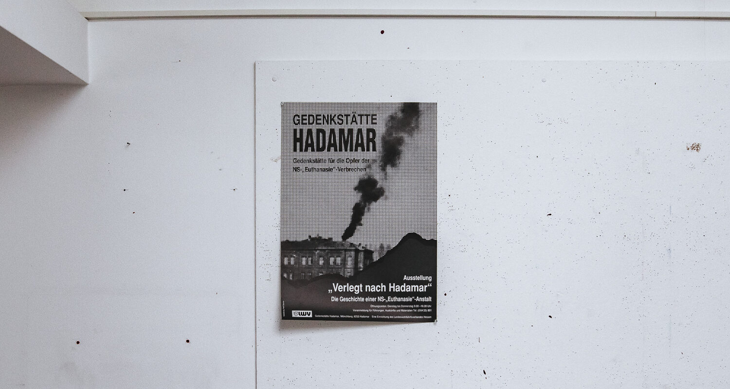 Ein altes schwarz-weiß-Plakat hängt an einer weißen Wand. Auf dem Plakat steht unter anderem "Gedenkstätte Hadamar"