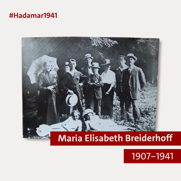 Eine Grafik mit einem beigen Hintergrund. In der oberen linken Ecke steht in roter Schrift "#Hadamar1941", in der rechten unteren Ecke sind zwei rote Balken übereinander, die in das Bild ragen. Auf dem oberen Balken steht in heller Schrift "Maria Elisabeth Breiderhoff", auf dem unteren Balken steht "1907-1941". In der Mitte der Grafik ist eine rechteckige Fotografie abgebildet. Auf dem schwarz-weißen Foto sind mehrere Menschen zu sehen, die für das Foto posieren. Links stehen zwei Frauen in dunklen Kleider, die vordere Frau hält einen Sonnenschrim. In der Mitte stehen vier Jungen, die Anzüge und Hüte tragen. Daneben steht eine einzlne Frau, die eine helle Bluse, einen dunklen Rock und einen dunklen Hut trägt. Auf der rechten Seite des Bildes stehen zwei Männer in Anzügen und mit Hüten auf dem Kopf. Vor der Gruppe liegen zwei Mädchen auf der Wiese und lächeln in die Kameta. Die Mädchen tragen helle Kleidung, eine von ihnen trägt einen hellen Hut. Das Foto wurde im Freien aufgenommen, im Hintergrund sind Äste von Bäumen zu sehen. Alle Mitglieder der Grippe schauen in die Kamera.
