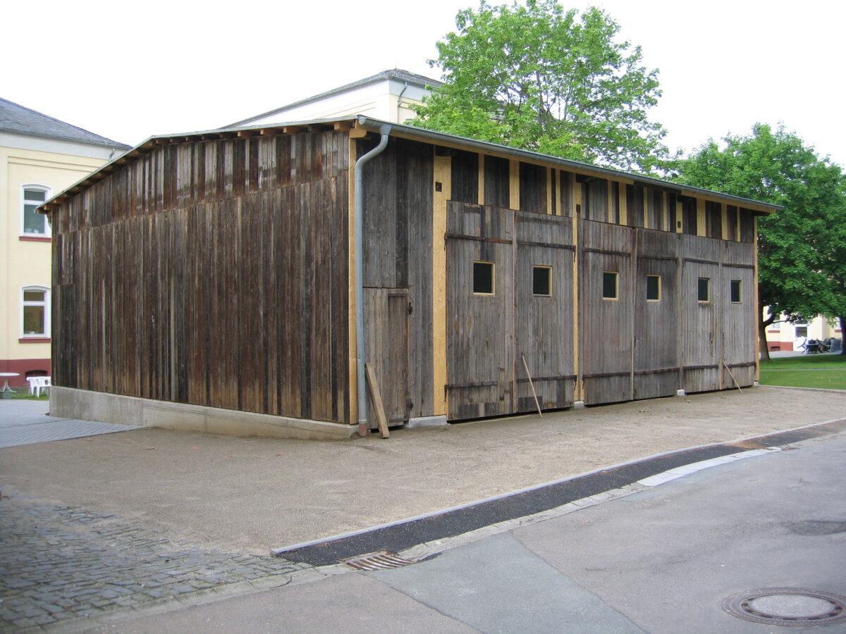 Die Busgarage im Innenhof der Gedenkstätte Hadamar. Die Tore sind geschlossen, auf der Vorderseite ist an einigen Stellen das helle Holz zu erkennen, wo die Garage ausgebessert werden musste.